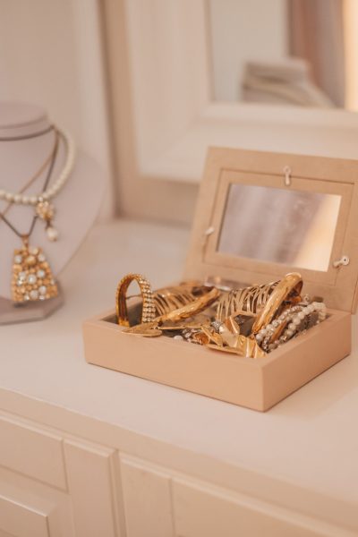 Luxury gold jewelry on set holders and in jewelry box on light dressing table and wardrobe shelves